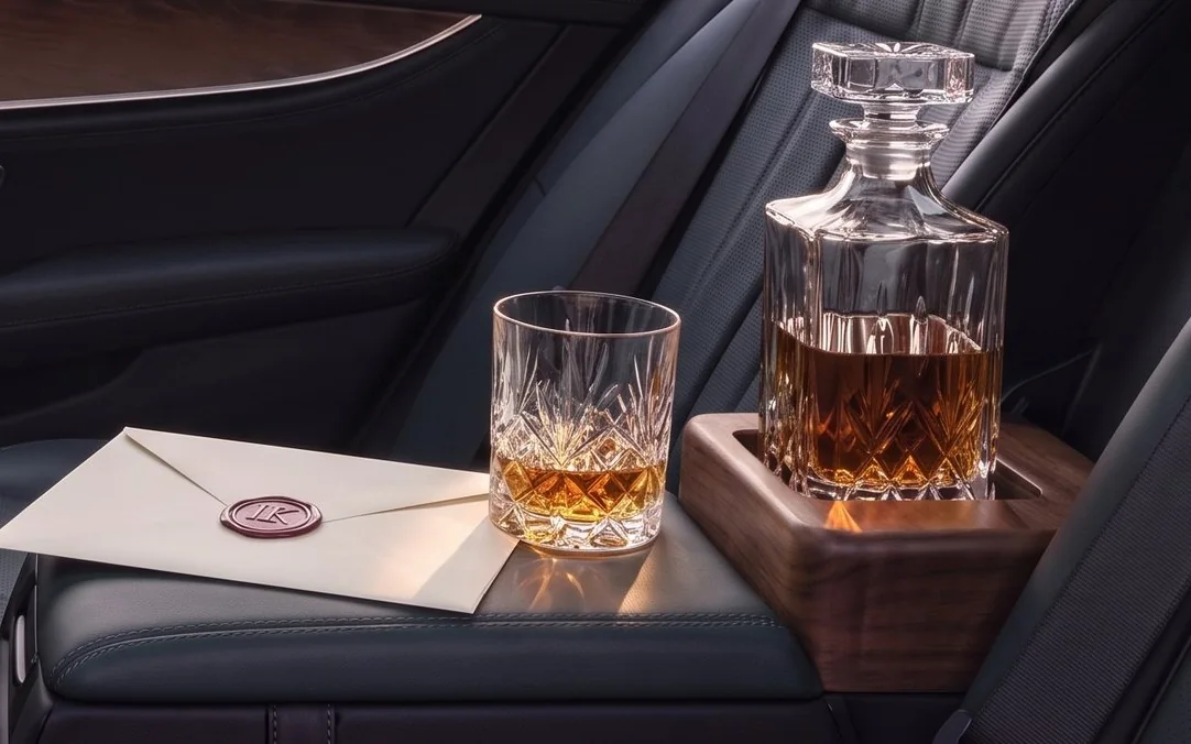 Kristallkaraffe mit Whisky und ein Glas auf einer Holzablage im Fond einer Limousine, daneben ein Umschlag mit Wachssiegel